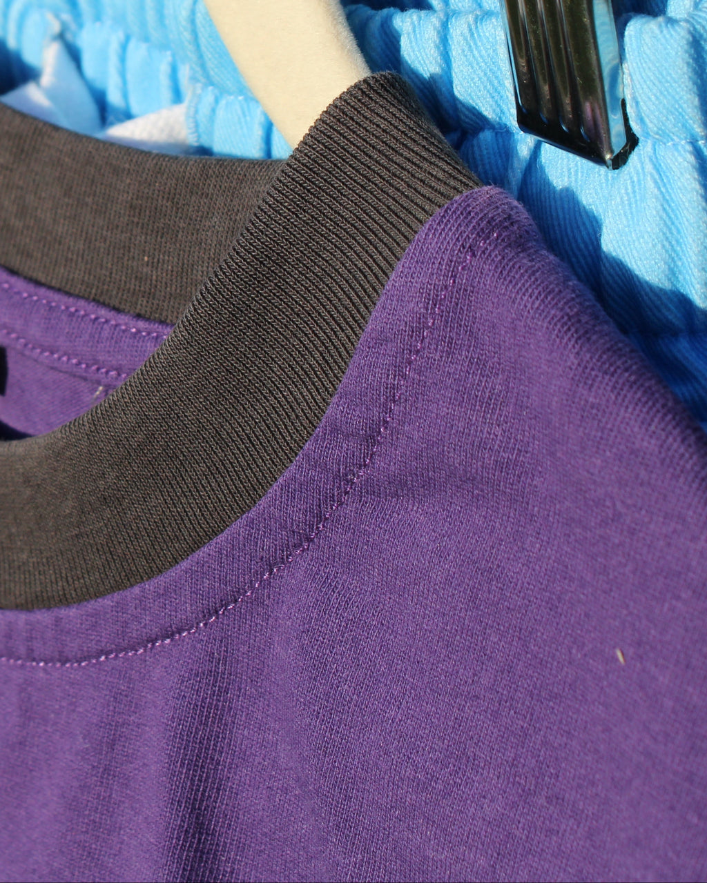 Purple shirt with black collar on a hanger