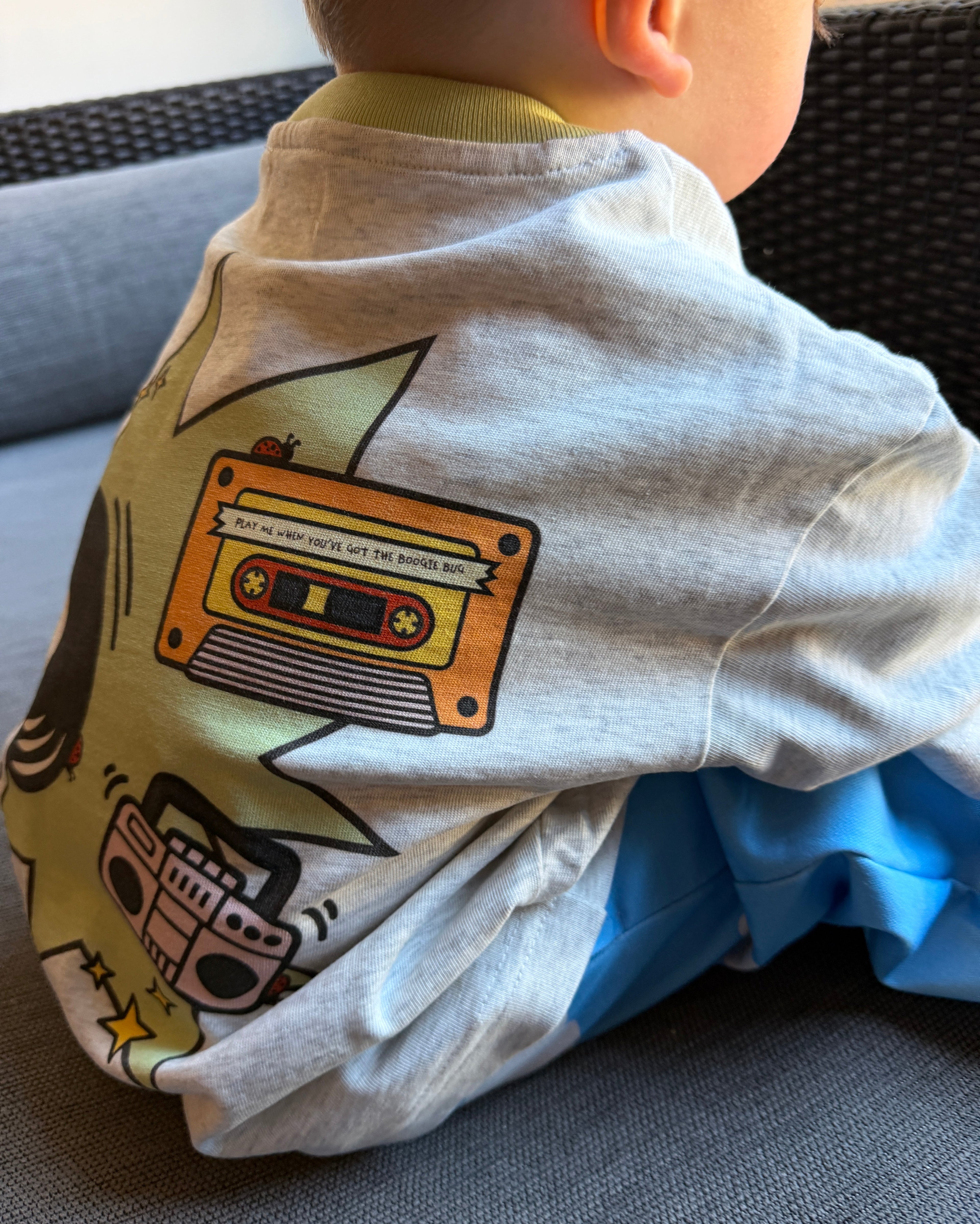 Child wearing a t shirt with a long sleeve stitched under it with a graphic design on a chair