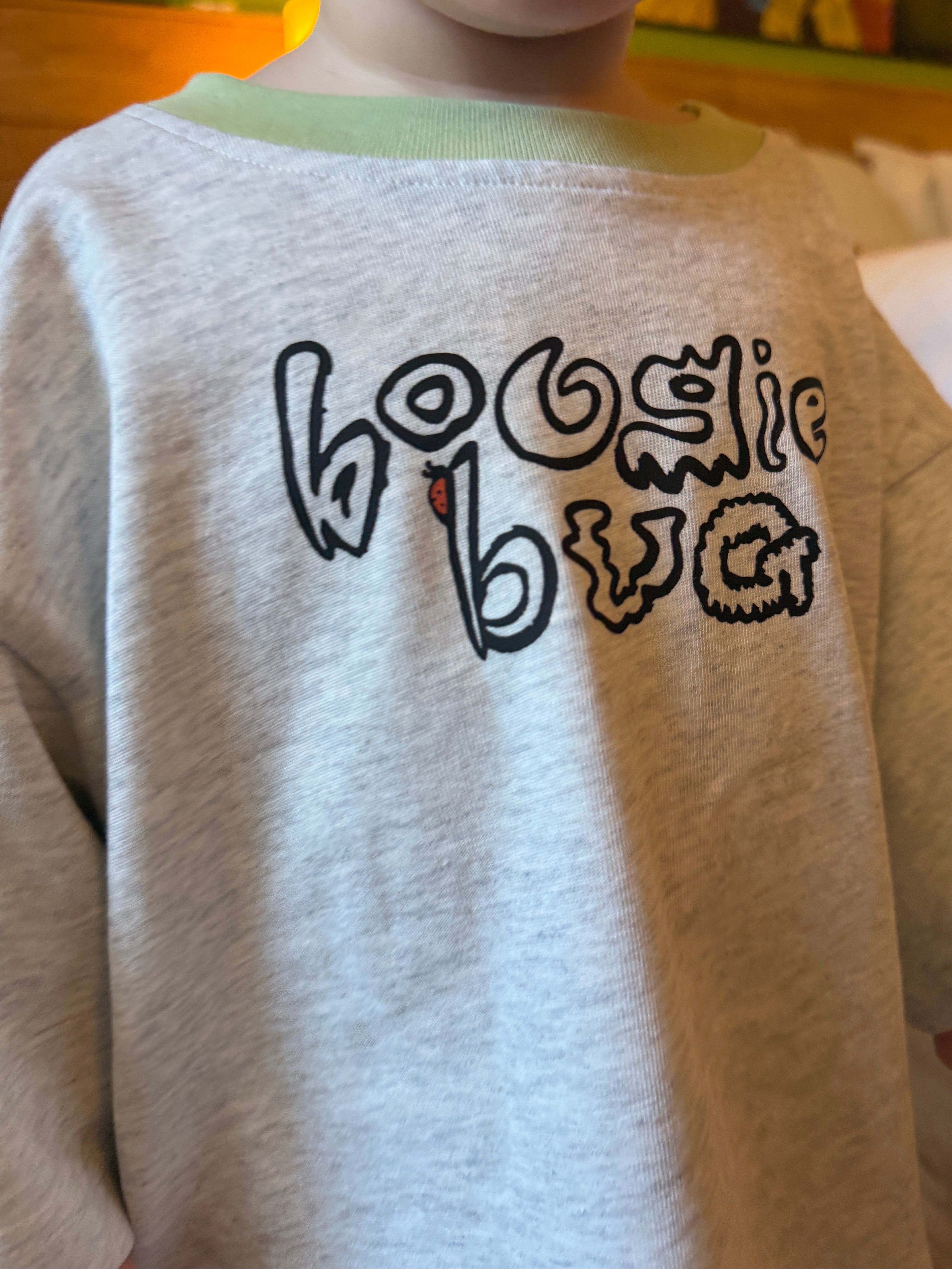 Child wearing a grey marle shirt with 'boogie bug' written on it