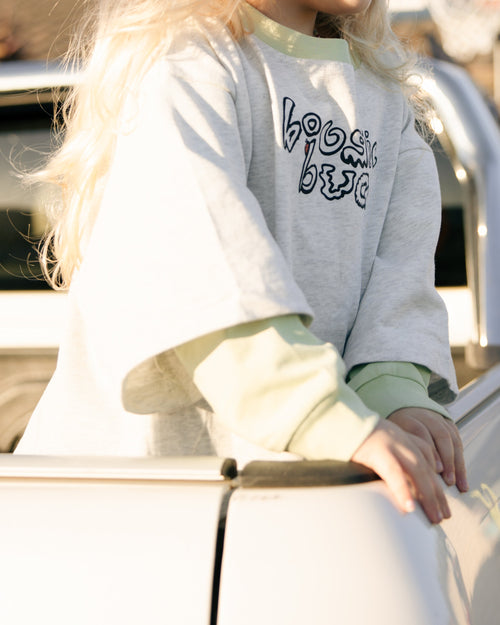 child in oversized grey marle t-shirt with a lime green long sleeve underneath