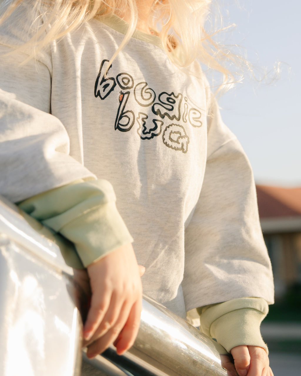 close up image of a girl wearing a grey marle t-shirt with a lime green long sleeve that reads 'boogie bug'