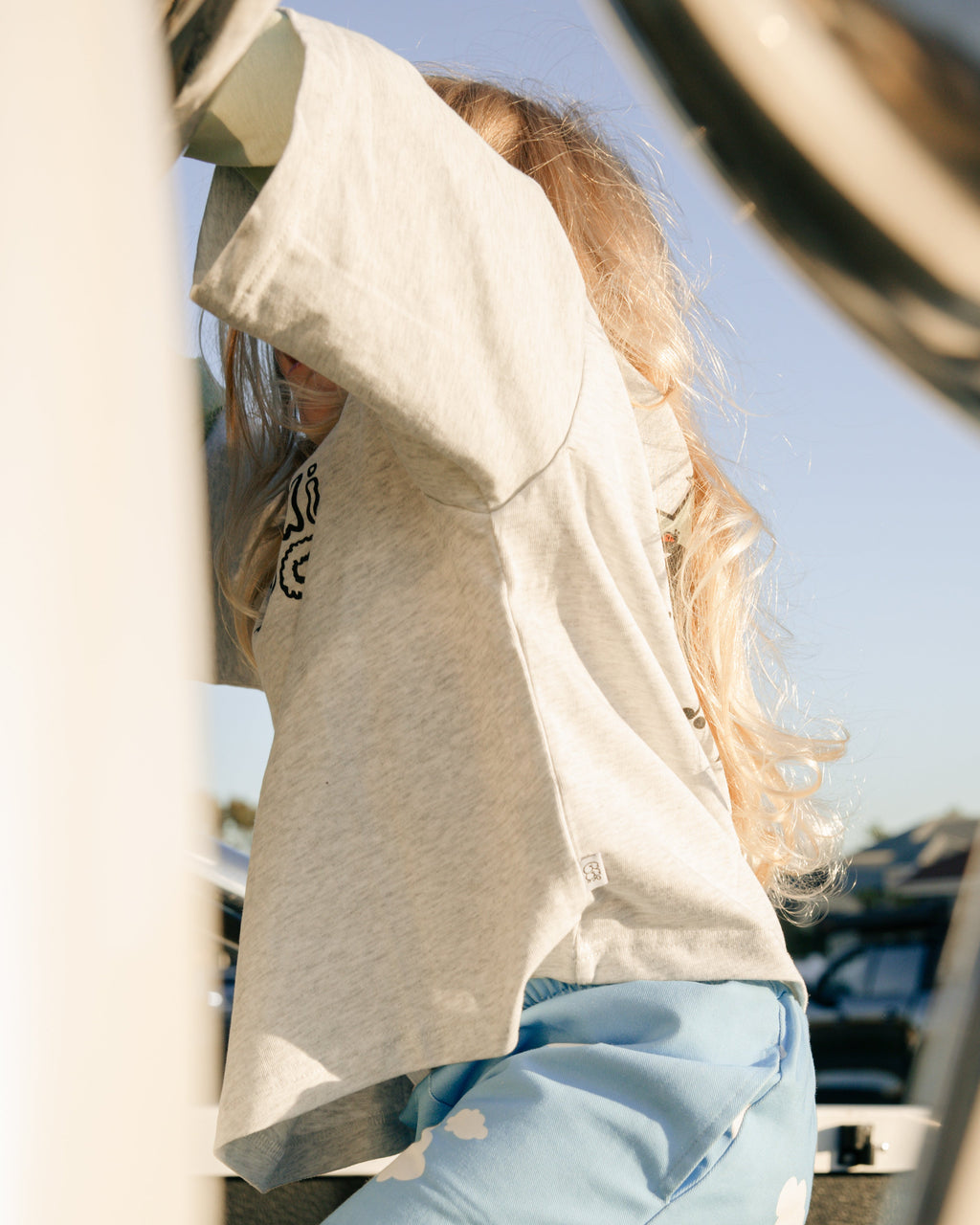 A child wearing a grey marle oversized t-shirt and blue pants