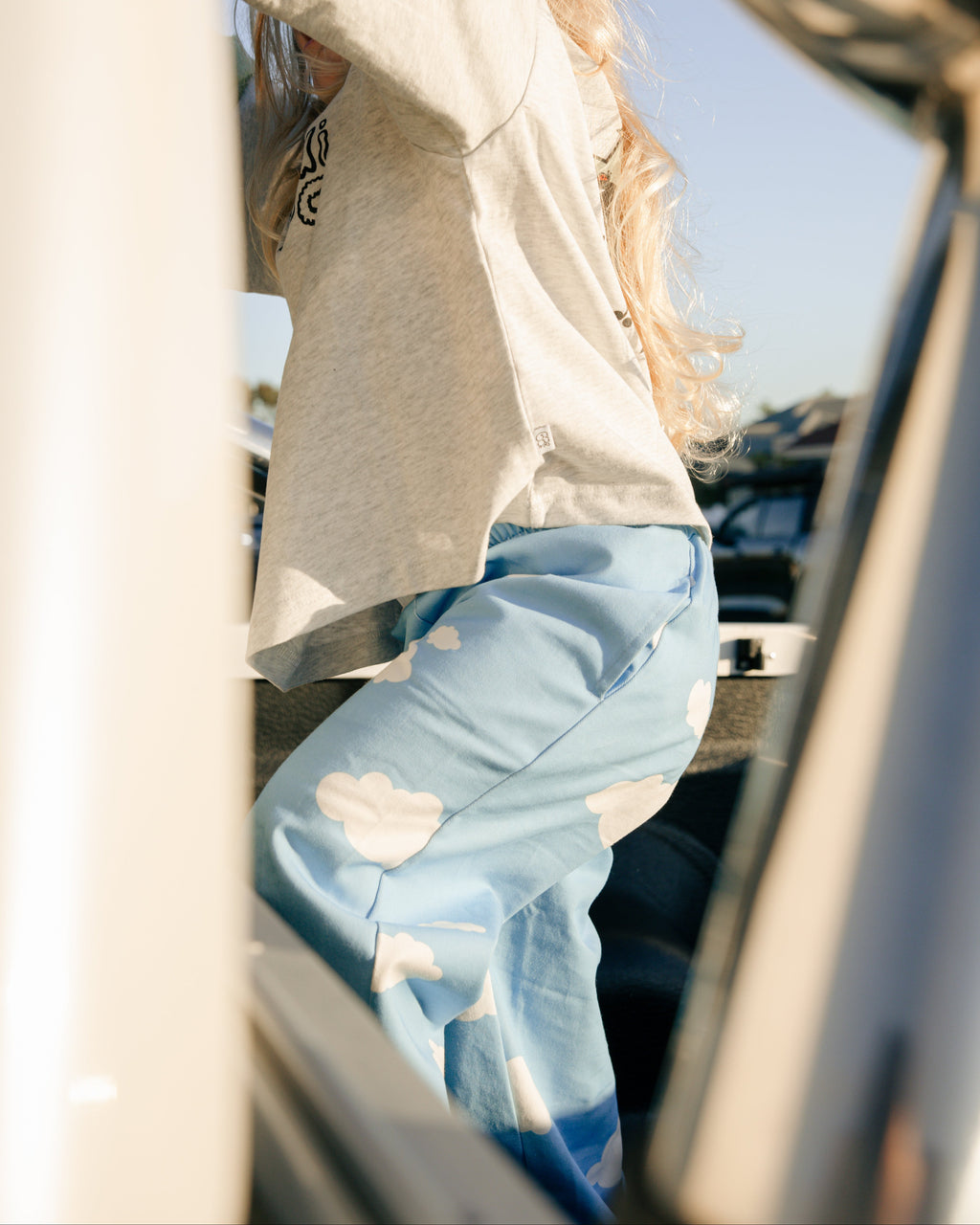 child wearing blue cloud pants in a car with a grey t-shirt