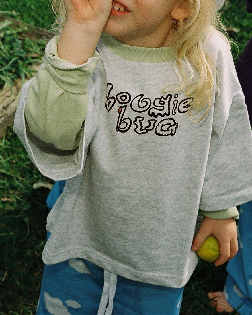 Child wearing a shirt with 'boogie bug' text, standing outdoors and holding a lime.